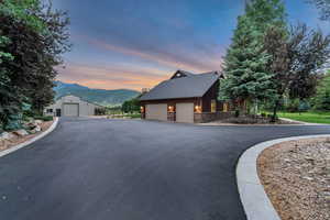 Property exterior at dusk with a mountain view, stone siding, and a garage
