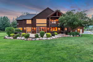 Back of house at dusk featuring a yard, a patio area, and an attached garage