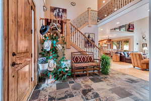 Stairway featuring a high ceiling, stone tile flooring, and recessed lighting