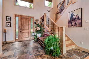 Entryway with a high ceiling, stairs, and stone tile flooring