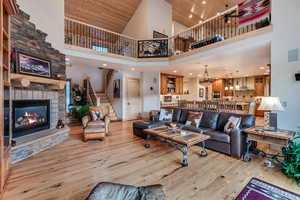 Living room with a high ceiling, stairs, wood finished floors, a fireplace, and wooden ceiling