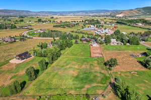 Aerial view of property and surrounding area featuring rural landscape and a mountainous background
