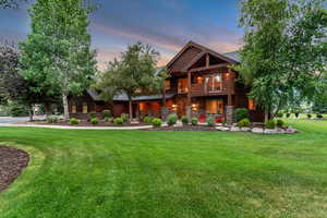 View of front of property with a balcony, a front lawn, and stone siding