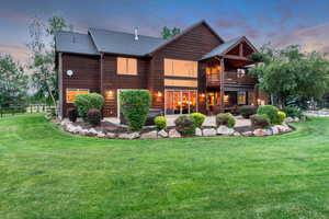 Back of house at dusk featuring a patio area, roof with shingles, and a deck