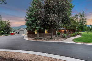 View of front of home featuring stone siding, a detached garage, an outdoor structure, a yard, and a mountain view