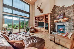 Living room featuring wood-type flooring, a fireplace, and high vaulted ceiling
