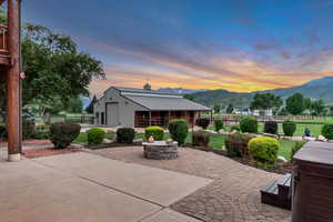 Patio terrace at dusk featuring a mountain view, an outdoor fire pit, an outbuilding, and a patio area