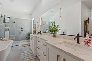Bathroom with vanity, a freestanding bath, a walk in shower, and tile patterned floors
