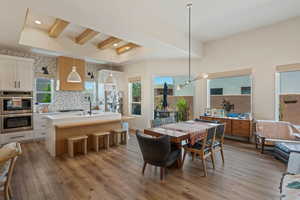 Dining space with light wood-style flooring, plenty of natural light, beam ceiling, recessed lighting, and a chandelier