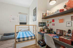 Bedroom with wood finished floors and a desk
