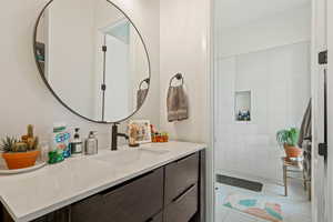 Bathroom featuring vanity, tiled shower, and tile patterned flooring