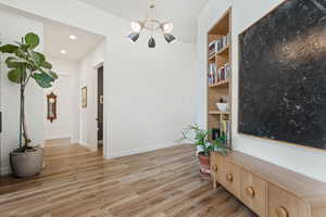Living area featuring a chandelier, light wood-style flooring, built in shelves, and recessed lighting