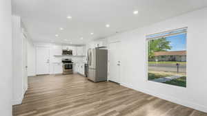 Kitchen featuring stainless steel appliances, recessed lighting, white cabinets, light wood-type flooring, and light countertops