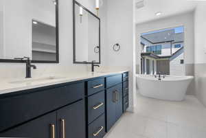 Full bathroom with double vanity, a freestanding tub, tile patterned flooring, and wainscoting