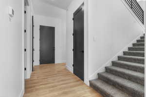 Hallway with stairs and light wood-type flooring