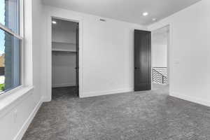 Unfurnished bedroom with carpet flooring, a spacious closet, recessed lighting, and a closet