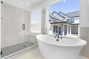 Full bathroom featuring tile walls, plenty of natural light, a freestanding tub, a shower stall, and tile patterned flooring