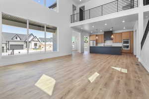 Unfurnished living room with light wood-type flooring and a high ceiling