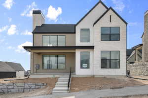 View of front of house with stone siding, roof with shingles, stucco siding, and a chimney