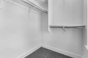 Walk in closet featuring dark colored carpet