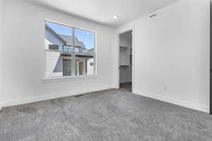 Unfurnished bedroom featuring a walk in closet and carpet flooring