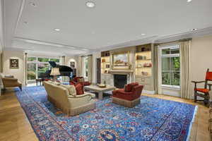 Living area featuring crown molding, recessed lighting, a fireplace, and light wood-type flooring