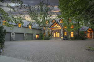 View of front of property with stone siding, decorative driveway, and stucco siding