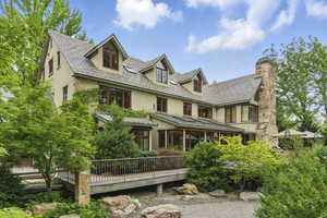 Back of house featuring stucco siding, a high end roof, a deck, a chimney, and a standing seam roof