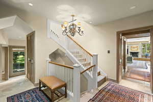 Staircase with plenty of natural light, a chandelier, recessed lighting, and a large fireplace