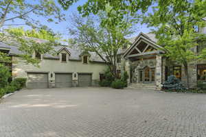 View of front of home featuring stone siding, stucco siding, a garage, decorative driveway, and french doors