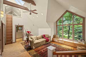 Living area featuring wood finished floors, a ceiling fan, high vaulted ceiling, and beam ceiling