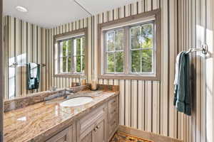 Bathroom featuring wallpapered walls and vanity