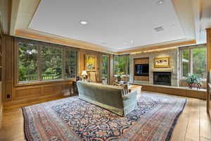 Living room with a tray ceiling, a fireplace, wood-type flooring, and recessed lighting