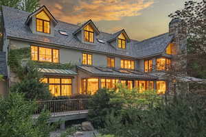 Back of house at dusk with a standing seam roof, a high end roof, a metal roof, and stucco siding