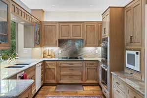 Kitchen featuring white appliances, light stone counters, decorative backsplash, light wood-style flooring, and recessed lighting