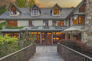 Back of property at dusk featuring a standing seam roof, stucco siding, french doors, and a high end roof