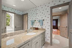 Bathroom with wallpapered walls, vanity, and tile patterned floors