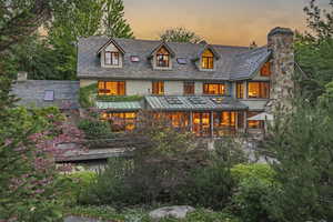 Back of property at dusk featuring a high end roof, stucco siding, and a standing seam roof