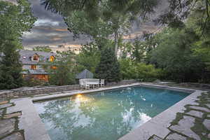 Pool at dusk with an outdoor pool, a patio, and a diving board
