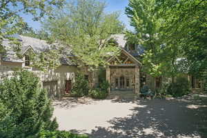 View of front facade featuring concrete driveway, stone siding, a high end roof, and a garage