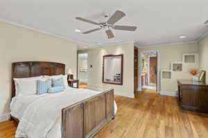 Bedroom featuring connected bathroom, light wood-style flooring, recessed lighting, ornamental molding, and a ceiling fan