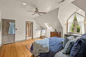 Bedroom with lofted ceiling, light wood-style flooring, a skylight, and a ceiling fan