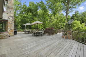 Wooden terrace with outdoor dining space and view of scattered trees
