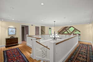 Hall with an upstairs landing, ornamental molding, a chandelier, light wood finished floors, and recessed lighting