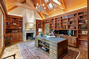 Office space with a chandelier, a wooden ceiling with exposed beams, built in features, high vaulted ceiling, and a large fireplace