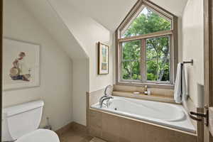 Full bath with vaulted ceiling, a garden tub, and tile patterned floors