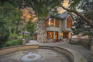 Rear view of house with stone siding, stucco siding, a wooden deck, and outdoor dining area