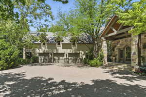 Rear view of house with stone siding, asphalt driveway, stucco siding, and a garage