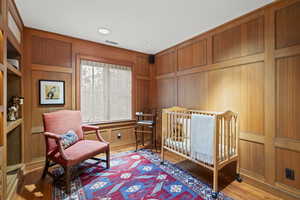 Bedroom featuring wood finished floors and a decorative wall