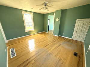 Unfurnished bedroom featuring light wood-type flooring, a textured ceiling, and ceiling fan